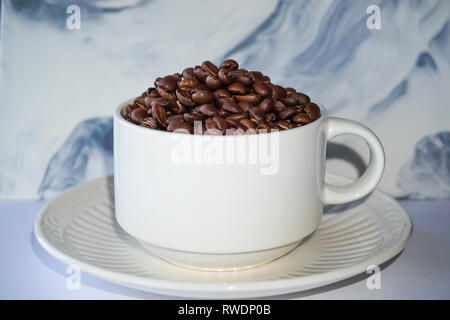 Weiße Tasse Kaffee mit Kaffeebohnen gefüllt. Stockfoto