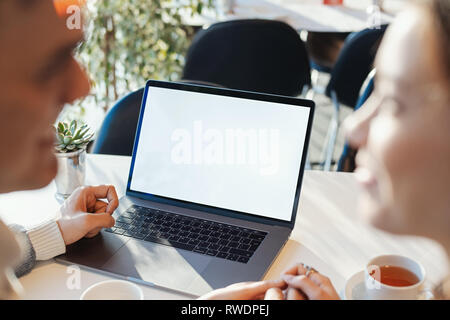 Junger Mann und Frau vor dem Laptop mit leeren weißen Bildschirm an. Team Meeting, arbeiten. Projektmanager in der Nähe der Fenster. Analysieren Business Stockfoto