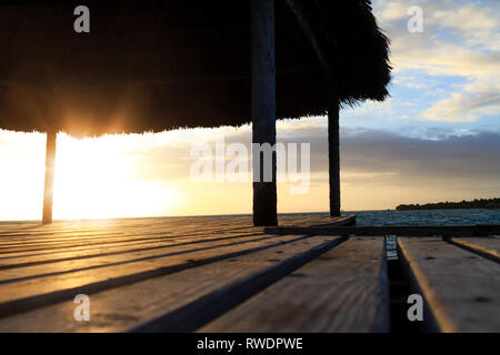 In der Nähe von Holz Pavillon am Strand bei Sonnenuntergang oder Sonnenaufgang. Hintergrund ist der Strand mit Palmen und blaues Wasser in den frühen Morgen. Multicolore Stockfoto