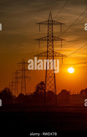 Hochspannungsmasten gegen das Licht bei Sonnenuntergang Stockfoto