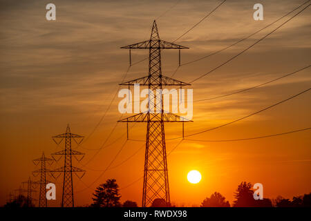 Hochspannungsmasten gegen das Licht bei Sonnenuntergang Stockfoto