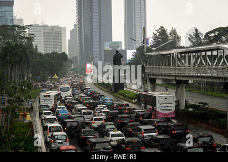 Jakarta, Indonesien - 16. November 2018: Stau entlang der Sudirman Road im Herzen von Jakartas Geschäftsviertel an einem regnerischen Tag mit Transjakarta Stockfoto