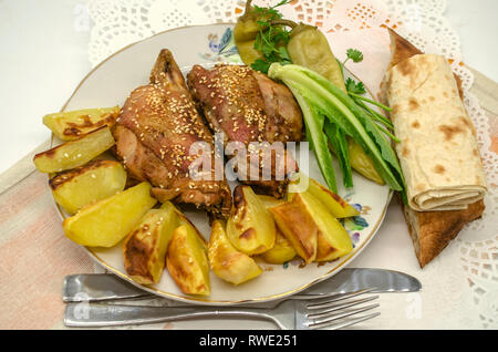 Im Ofen gebacken Stücke vom Huhn mit Kartoffeln sind gewürzt mit weißer Sesam und schwarzem Pfeffer mit Salat, marinierte Paprika auf der großen Platte, Stockfoto