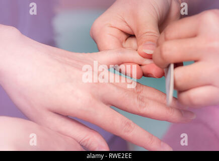 Frauen, die Fingernägel Maniküre Service durch professionelle Maniküre im Nagelstudio. Kosmetikerin Datei Nagel Maniküre im Nagel und Spa Salon. Hand Care Stockfoto