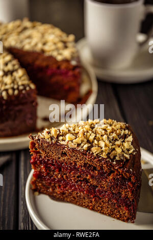 Hausgemachte Kuchen mit Schokoladenglasur und Walnüsse in Scheiben schneiden und Kaffee. Selektive konzentrieren. Stockfoto