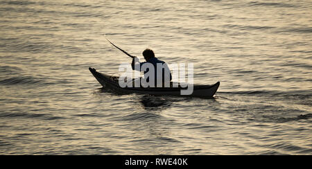 Ein einsamer Mann paddelt ein Kajak bei Sonnenuntergang in Silhouette Auf ruhigem Wasser mit Kopie Raum Wasser Vollformat Stockfoto