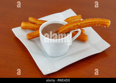 Traditionelle spanische Churros mit heißer Schokoladensauce auf einem rustikalen Holztisch Stockfoto