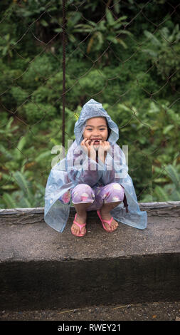 Lächelnd wenig philippinischen Mädchen im Regenmantel - Banaue, Ifugao, Philippinen Stockfoto