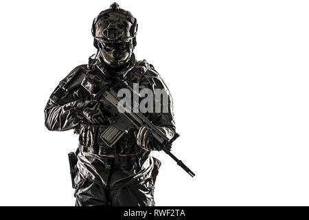 Desatured studio geschossen von einer Armee Soldat in Schutzmaßnahmen gegen einheitliche Holding Assault Rifle. Stockfoto