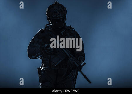 Silhouette einer Armee Soldat in Schutzmaßnahmen gegen einheitliche Holding Assault Rifle. Stockfoto