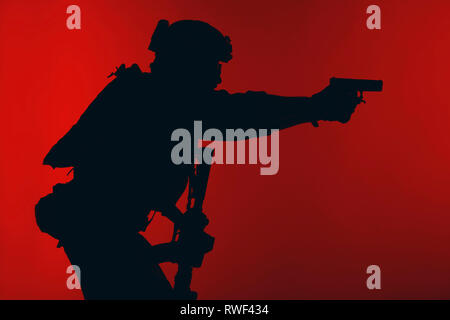 Silhouette eines US Marine Corps Marsoc Raider darauf abzielt, Pistole, roten Hintergrund. Stockfoto