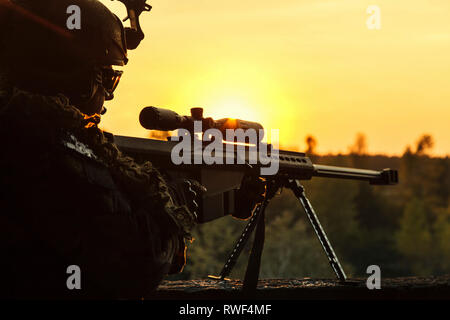 Silhouette von Army Sniper mit großkaliber-Gewehr gegen Sonnenuntergang. Stockfoto