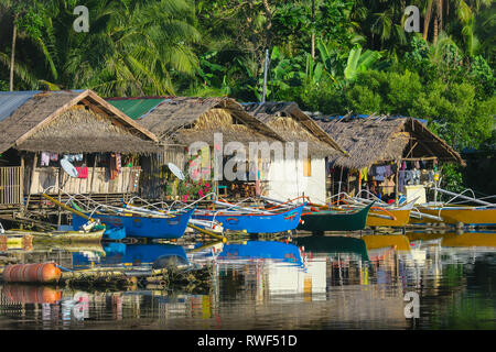 Bunte Boote aus Holz geparkt bei einheimischen Häusern im Rustikalen philippinische Dorf - Siargao, Philippinen Stockfoto