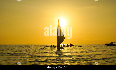 Segelboot mit Sitzen Touristen auf goldenen Sonnenuntergang Meer - Insel Boracay, Panay - Philippinen Stockfoto