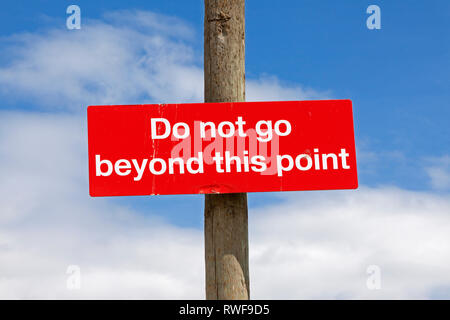 Ein Schild "Nicht über diesen Punkt hinaus" gegen einen blauen Himmel gesehen. Stockfoto