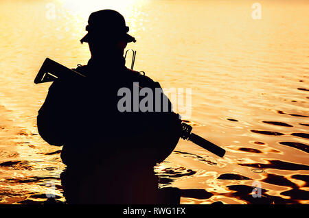 Silhouette einer Special forces Soldat mit Gewehr, einen Fluß überquert im Dschungel. Stockfoto