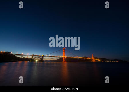 Golden Gate Bridge von Straßenlaternen aus dem Wasser ragt beleuchtet nach Sonnenuntergang Stockfoto