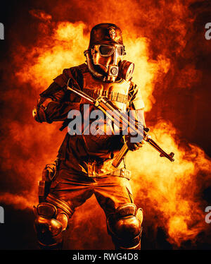 Futuristische NS-Soldat trägt eine Gasmaske und eine Maschinenpistole in Feuer und Rauch. Stockfoto