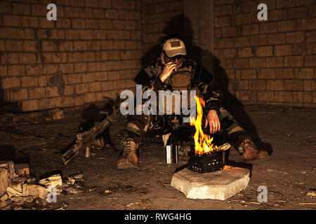 Special forces Soldaten das Rauchen einer Zigarette, während durch das Feuer in einem zerstörten Gebäude. Stockfoto