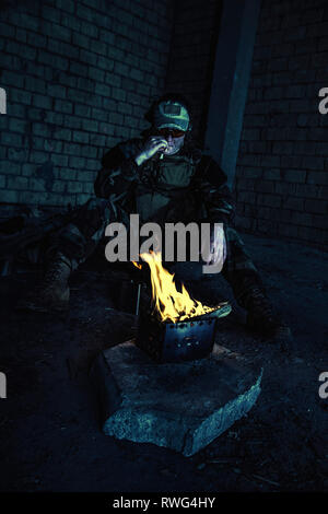 Special forces Soldaten das Rauchen einer Zigarette, während durch das Feuer in einem zerstörten Gebäude. Stockfoto