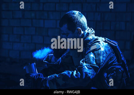 Special forces Soldaten das Rauchen einer Zigarette, während sie sich in einer Ruine sitzen. Stockfoto