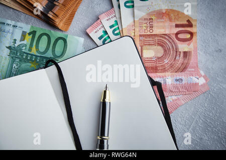 Geöffnet Notebook mit viel Euro Geldschein auf den Tisch Close-up Top View Business Konzept Stockfoto