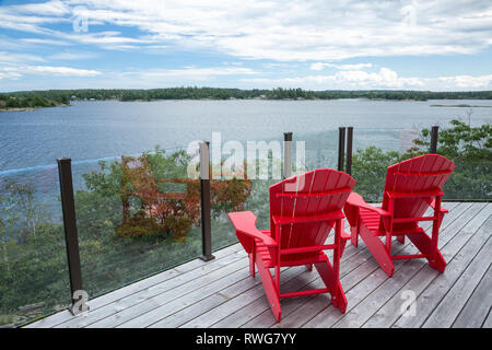 Red Muskoka Stühle an Deck mit Blick auf die Bucht von Inseln, Whitefish Falls, Ontario, Kanada. Stockfoto