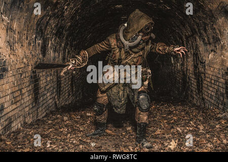 Mutierten Kreatur in Fetzen und Gasmaske springt aus der Dunkelheit in einem verlassenen Tunnel. Stockfoto