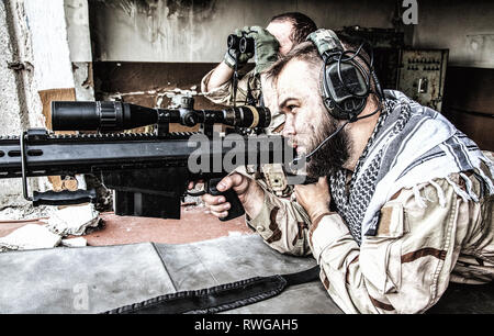 Navy SEAL Sniper team engagieren Ziele aus einem zerstörten Gebäude mit einem Scharfschützengewehr. Stockfoto