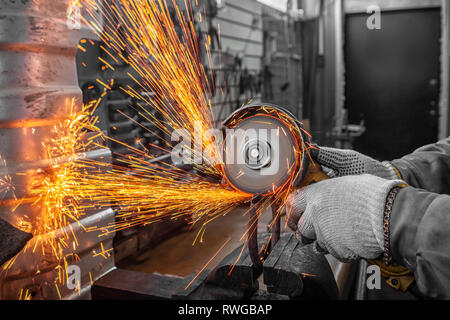 Nahaufnahme eines Mannes sägen Metall Lager mit einer Handkreissäge, helle Blitze fliegen in verschiedenen Richtungen, im Hintergrund Tools für ein Auto Stockfoto