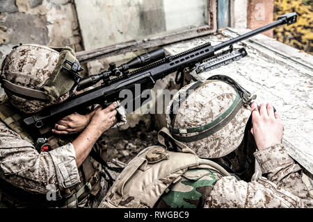 Sniper team Shooting feindliche Ziele mit Scharfschützengewehr aus einem zerstörten städtischen Gebäude. Stockfoto