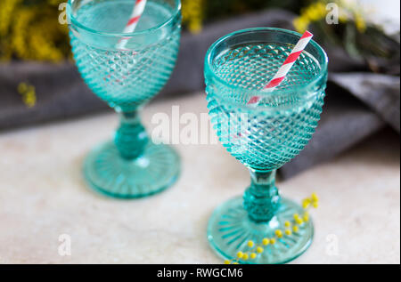 Refhesing Drink in Blue vintage Kelche auf dem weißen Hintergrund mit srping Blumen. Mimosen, Blumen Stockfoto