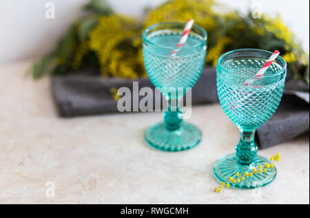 Refhesing Drink in Blue vintage Kelche auf dem weißen Hintergrund mit srping Blumen. Mimosen, Blumen Stockfoto
