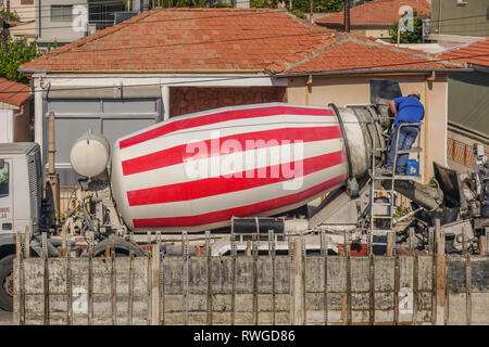 Limassol, Zypern - 3. April 2018: Rot-weiß gestreiften Betonmischer LKW mit einem Mann an der Rückseite arbeiten Stockfoto