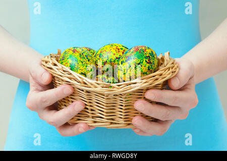 Kaukasische Mädchen hält in der Hand einen Korb mit Ostern gelbe Eier bemalt. Close-up. Stockfoto