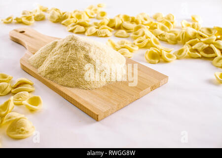 Close-up Orecchiette typisch italienische Pasta mit einem Stapel von Hartweizen Mehl auf Holz Schneidebrett Stockfoto