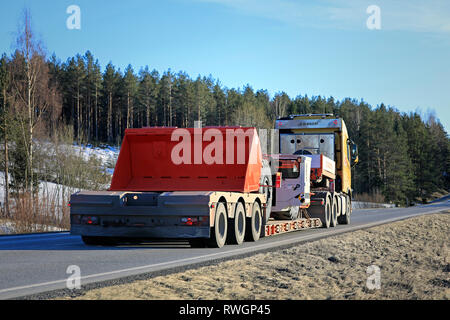 Salo, Finnland - 1. März 2019: Volvo FH Truck von Silvasti hols Sandvik LH 209 L U-Lader oder LHD am Anhänger auf der Autobahn im Frühjahr, Sicht nach hinten. Stockfoto