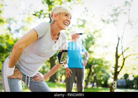 Gerne reifes Paar stretching beim Laufen im Park Stockfoto