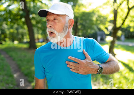 Ältere Menschen mit Schmerzen in der Brust leiden von Herzinfarkt beim Joggen Stockfoto
