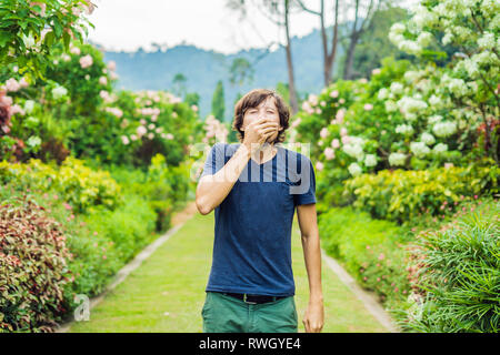 Junger Mann blasen Nase vor der blühenden Baum. Frühling Allergie Konzept Stockfoto