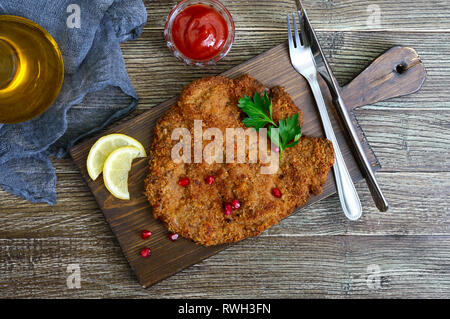 Große Wiener Schnitzel auf einer hölzernen Hintergrund. Fleischgericht. Ansicht von oben, flach. Stockfoto