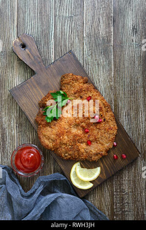 Große Wiener Schnitzel auf einer hölzernen Hintergrund. Fleischgericht. Ansicht von oben, flach. Stockfoto