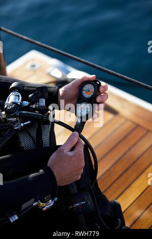 In der Nähe der Taucher mit Ausrüstung an Bord Boot, Hände halten Oxygen Regulator-pre dive Checks Stockfoto