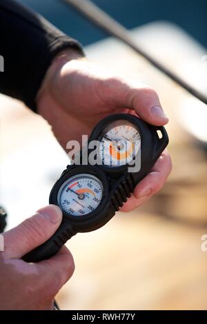 Extreme Nahaufnahme von Diver's Hände Kontrolle Sauerstoff Manometer Druckregler an Bord Boot Stockfoto