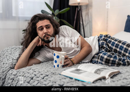 Traurige nachdenkliche junge Mann trinken heißen Tee Stockfoto