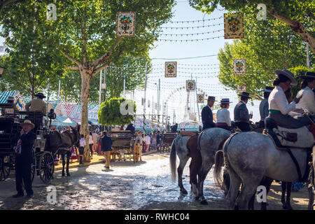 Reiter und Menschen in traditionellen Kostümen genießen April Messe. Sevilla Messe (Feria de Sevilla). Stockfoto