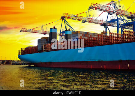 Containerschiff im Hafen unter der Belastung bei Sonnenaufgang. Stockfoto