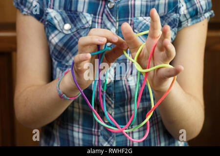 Kind spielen Classic, old-school string Spiel und didaktisches Spielzeug mit den Fingern, Erzeugen von Formen, ihre motorischen Fähigkeiten zu entwickeln. IQ, Bildung, intellig Stockfoto