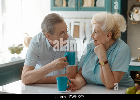 Senior paar Tee trinken und mit einem aufrichtigen Gespräch in den Speisesaal. Positive Emotionen, Liebe und Harmonie. Stockfoto