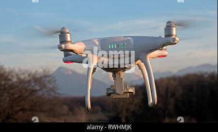 Eine Drohne schwebt im Flug vor einem Sonnenuntergang Hintergrund. Die drohne ist stationär schweben über dem Boden wie die Sonnenuntergänge in der Ferne. Stockfoto